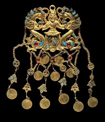 One of a pair of pendants depicting the "Dragon Master" (Tillya Tepe, Tomb II), 1st century BC - 1st century AD (cat. No. 61) gold, turquoise, garnet, lapis lazuli, carnelian and pearl, 5.2 x 6.9 x 1.1 cm (2 1/ 16 x 23/ 4 x 7/ 16); overall length of 2 pendants: 12.1 cm (4 4/ 4); disk diameter: 1.2 cm (1 / 2)  - National Museum of Afghanistan © Thierry Ollivier / Musée Guimet