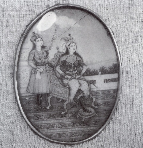 Auf Elfenbein gemalte Miniatur: gerüstete Dame mit Dienerin - Indien, wohl Mitte 19. Jh. Das Bild der auf einer Terrasse sitzenden Dame, hinter der eine Dienerin mit dem weit verbreiteten Fliegenwedel steht, ist zweifellos vielfältig beeinflußt von europäischen Maltraditionen: angefangen bei dem ovalen Bildformat, der Miniaturgröße, über die Verwendung westlichen Mobiliars bis hin zur Art der Farbperspektive im Fernblick über der Terrasse. Das ikonographisch merkwürdige Faktum, daß die reich gewandete und geschmückte Dame ein Schwert hält und auch teilweise gerüstet erscheint, mag einmal bei der genauen Bestimmung des Bildinhaltes und der Benennung der Hauptfigur hilfreich sein. 11,5 x 9,5 cm; Foto: Hans-Joachim Risto